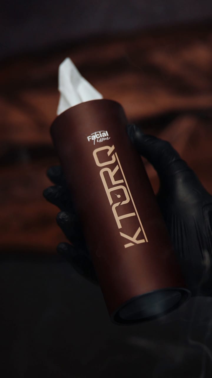 A hand pulling one tissue from the KTORQ car tissue tube